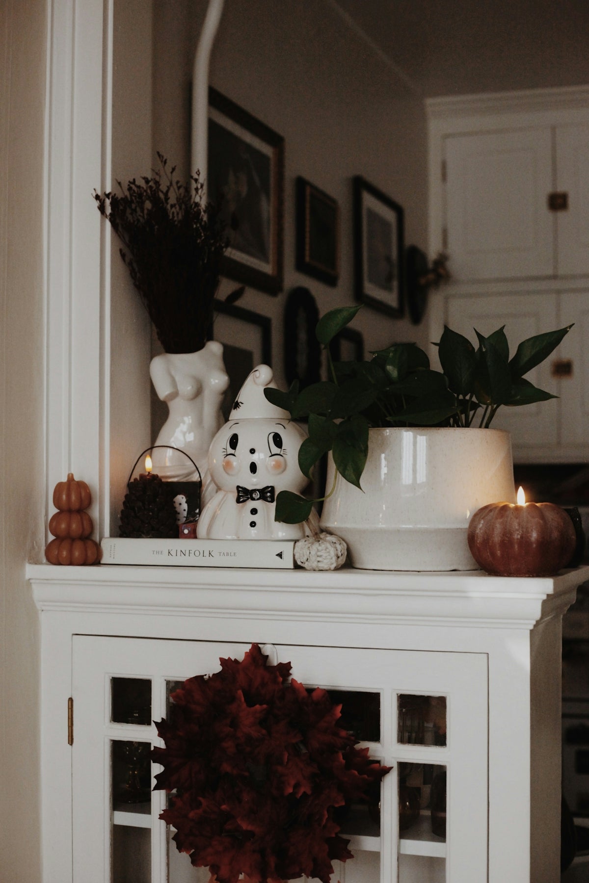 Spooky ghost, pumpkins, and fall decor on a white cabinet